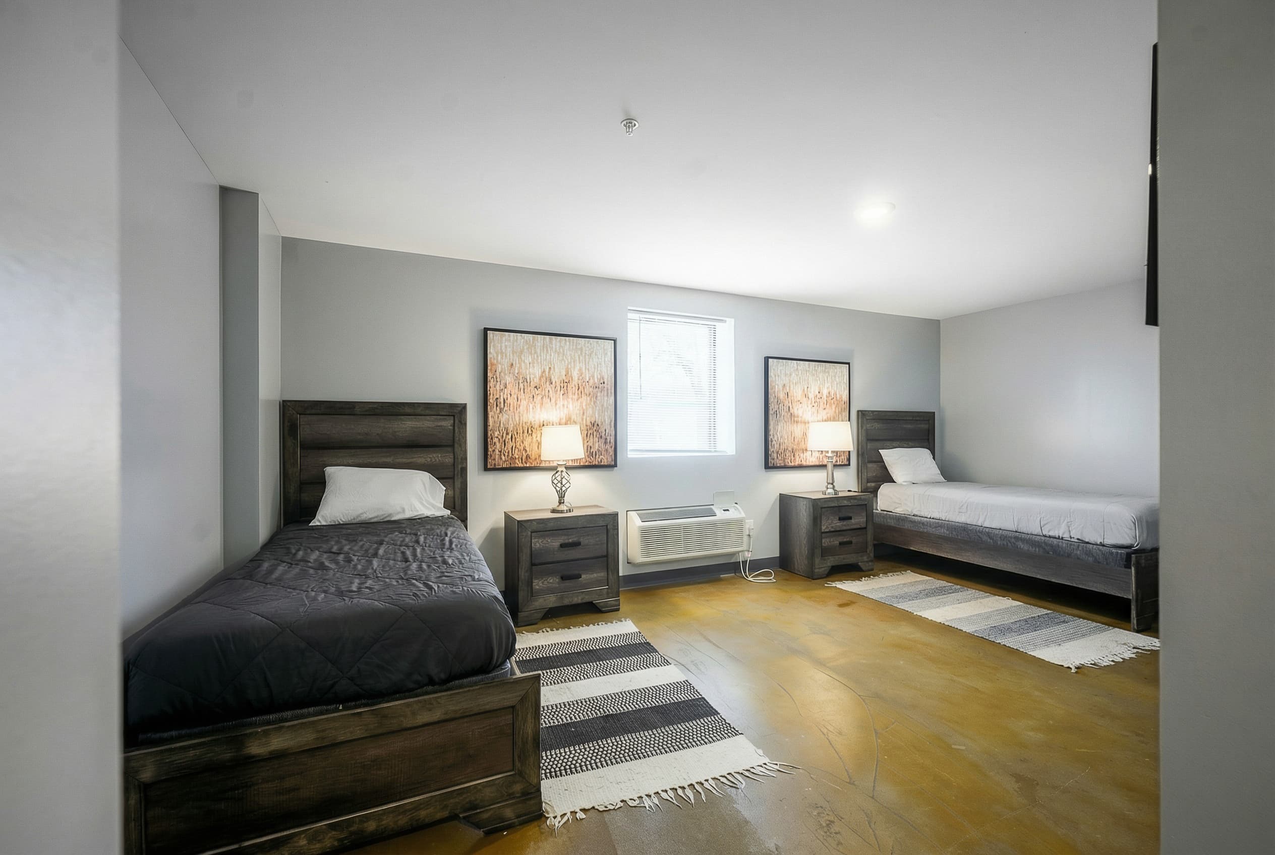 Shared bedroom with two twin beds, side tables, and framed art at Natural State Recovery Centers