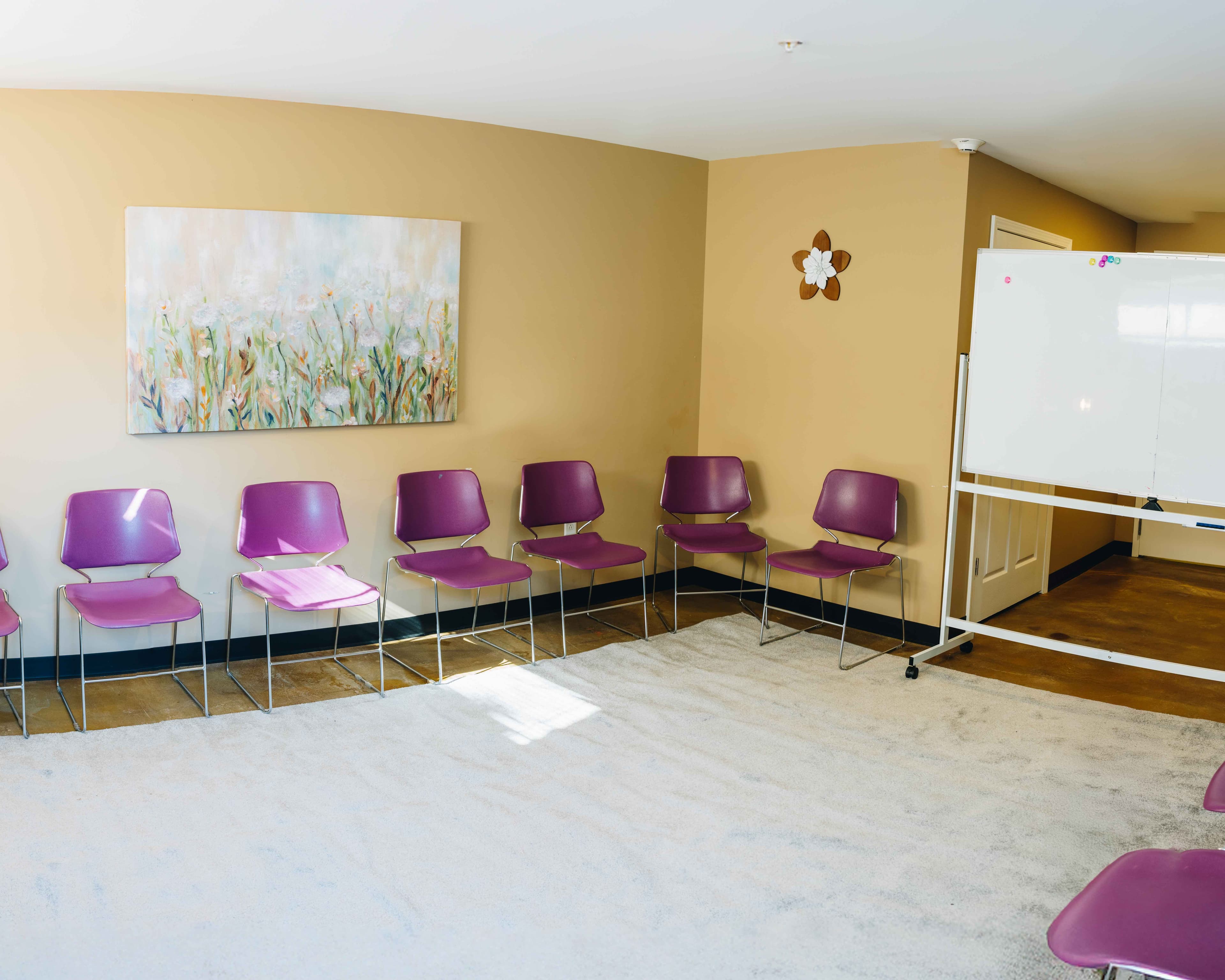 Group therapy room with purple chairs, framed art, and a whiteboard at Natural State Recovery Centers