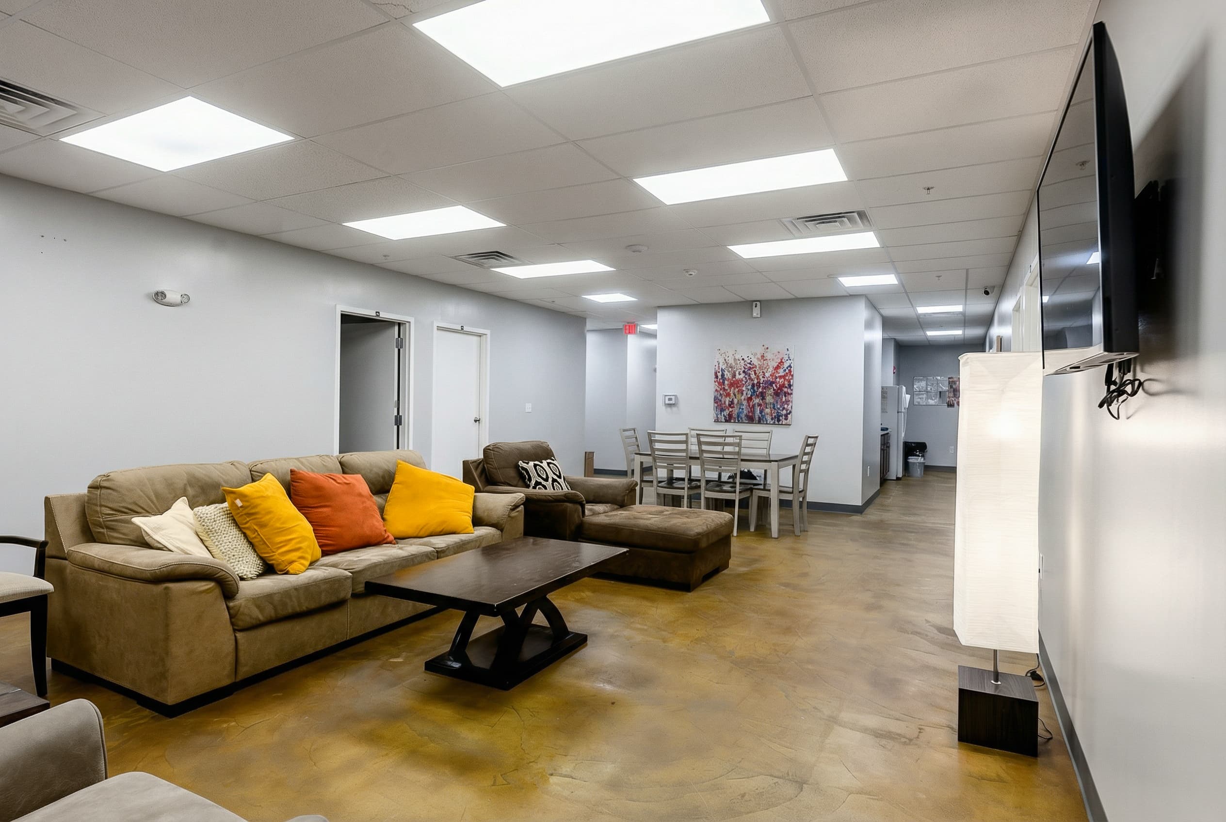 Bright, spacious common room with sectional seating and a dining table at Natural State Recovery Centers